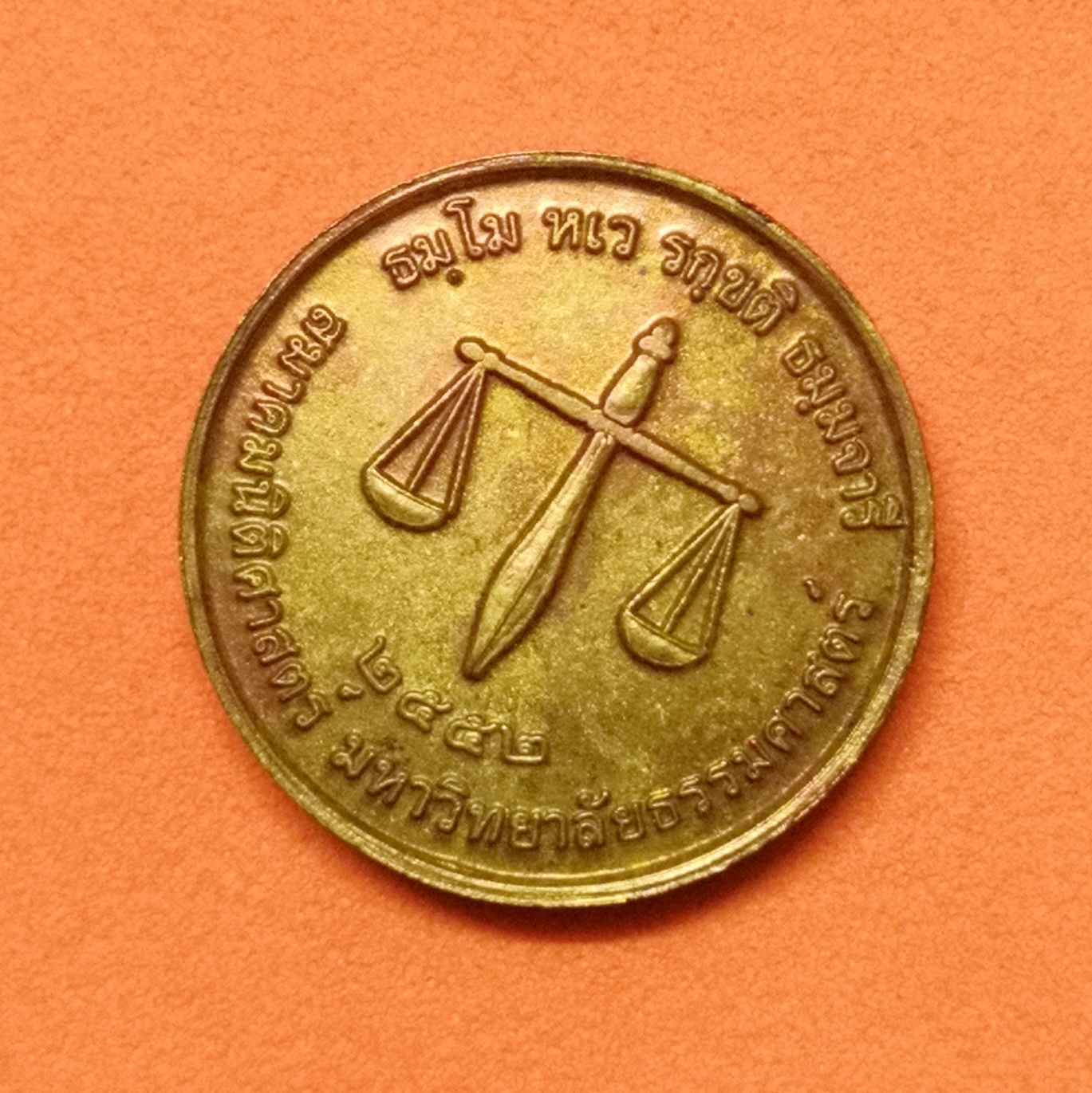 เหรียญเล็ก ขนาด 1.7 เซน พระพุทธโลกนิติธรรมเทสก์ หลัง ตาชั่ง สมาคมนิติศาสตร์ มหาวิทยาลัยธรรมศาสตร์ พศ 2552 เนื้อทองแดง